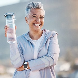 Woman smiling with water bottle on hike outside