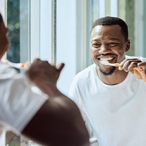 Man smiling while brushing his teeth