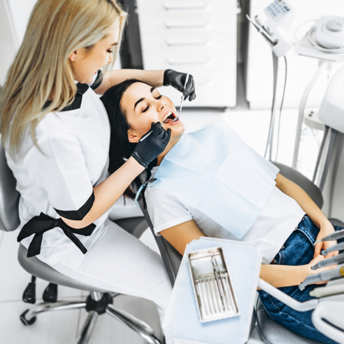 Dentist sitting next to patient and performing checkup