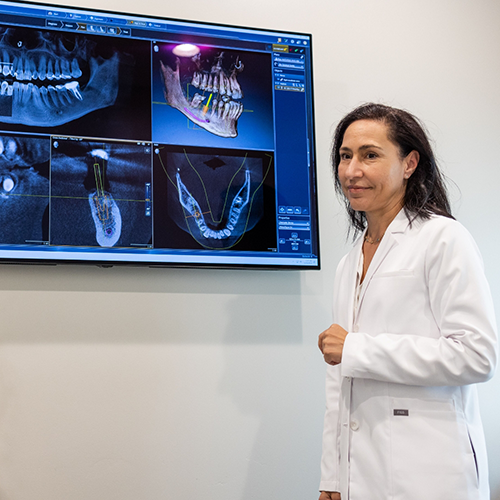 Woman sitting at computer monitor looking at X-rays of teeth