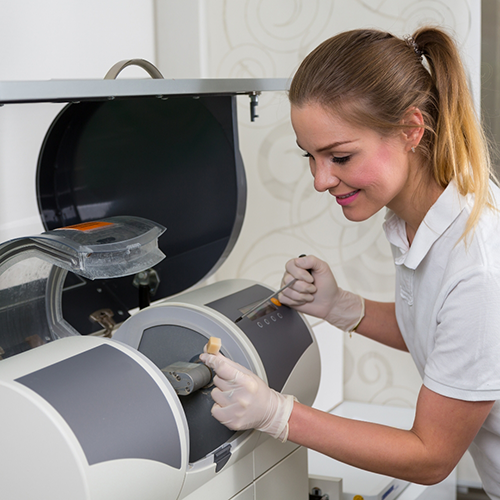 Female dentist placing ceramic block in CEREC machine