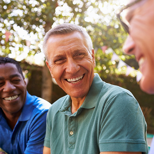 Three men sitting outside and smiling