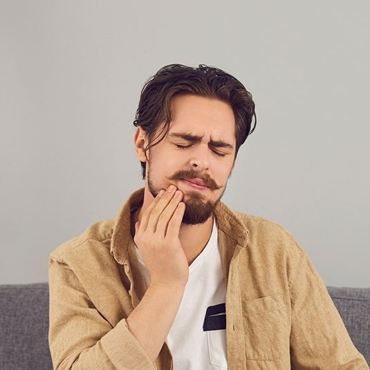 Man with beard rubbing jaw in pain