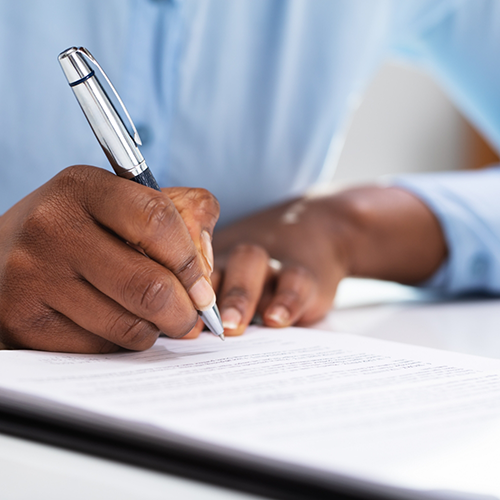 Close-up of man writing on a form with a pen