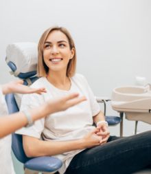 Woman in white shirt smiling and looking up at dentist