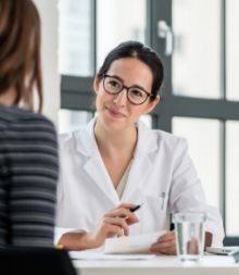 Team member with glasses talking with patient at front desk of dental office