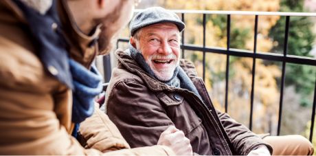 Man in hat smiling and talking to another man