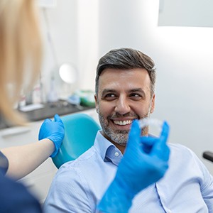 Patient smiling at dentist holding clear aligner