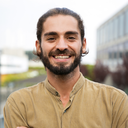 Man in collared shirt standing outside smiling