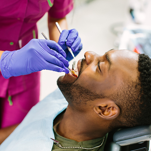 Male dental patient holding mouth open for checkup